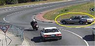 Intersections - The motorcyclist wants to travel straight ahead through this roundabout. The rider should watch out for the marked car because the car: